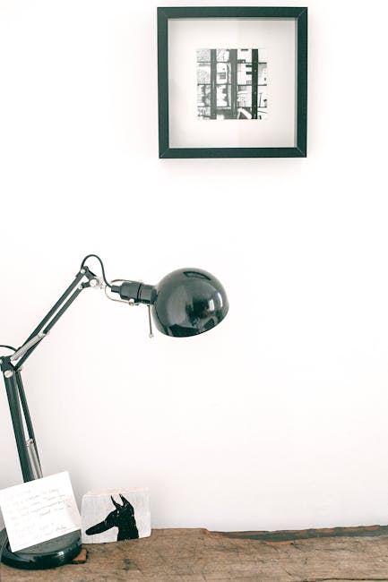 Modern minimal workspace with a desk lamp against a white wall.